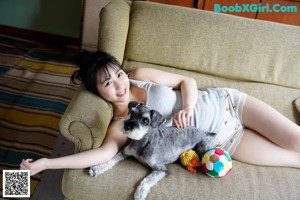 A woman in a gray tank top and white shorts posing by a window.