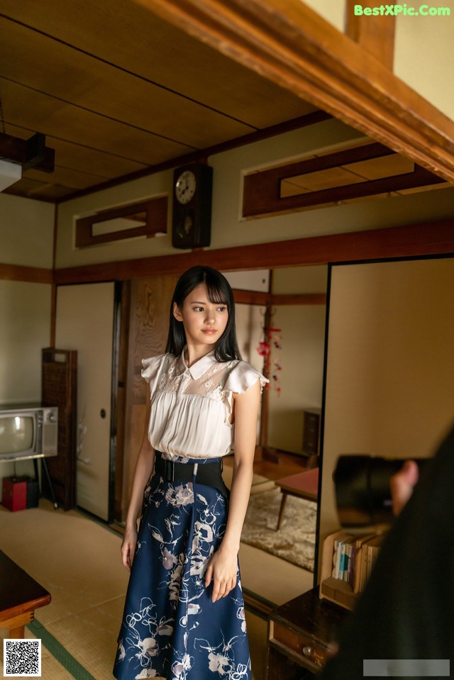 A woman standing in a room next to a television.