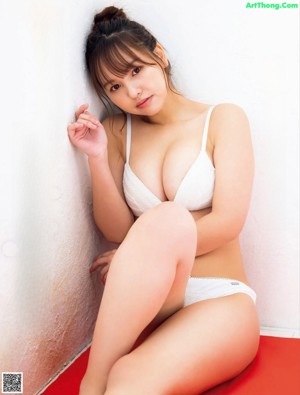 A woman in a white bra and panties sitting on a red mat.