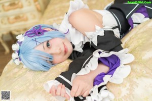 A woman in a maid outfit posing on a bed.