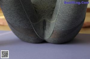A woman sitting on a yoga mat in a room.