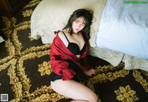 A woman in a white robe sitting on a bed.