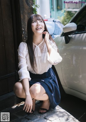 A naked asian woman leaning against a window.