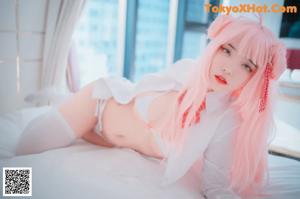 A woman with long pink hair in a bikini posing for a picture.