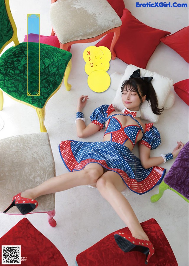 A woman in a red, white and blue polka dot dress laying on a couch.
