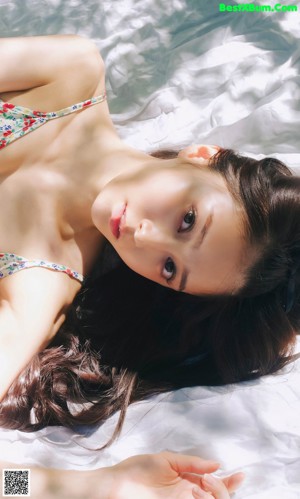 A woman in a white bikini laying on a mat.