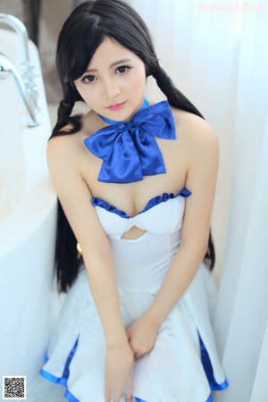 A woman in a white dress with a blue bow.