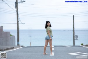A naked asian woman standing in front of a window.