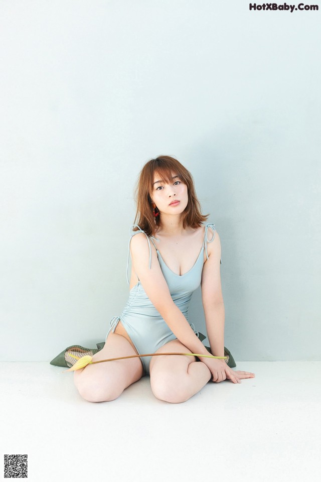 A woman in a blue bathing suit sitting on the floor.