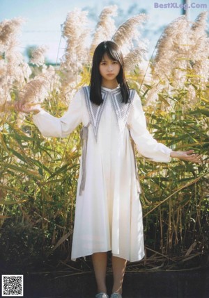 A young woman standing in front of a body of water.