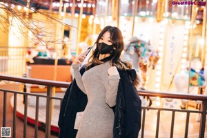 A woman wearing a face mask standing on a bridge.
