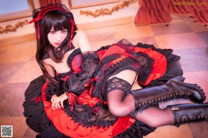A woman in a black and red dress sitting on a red couch.