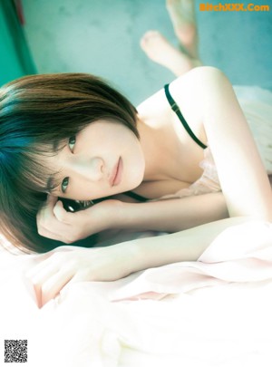 A woman laying on top of a bed next to a window.