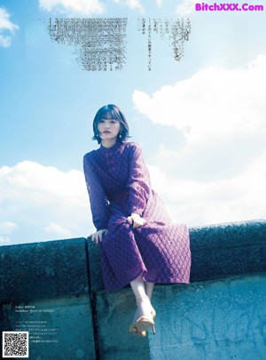 A woman laying on top of a bed next to a window.