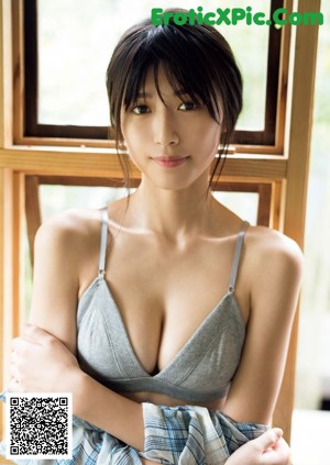A woman in a gray bra top sitting on a window sill.