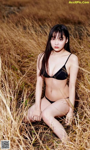 A woman in a black tank top is looking away from the camera.