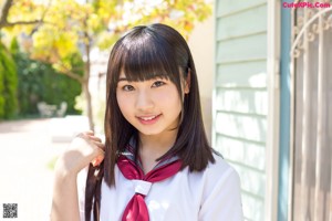 A woman in a school uniform sitting next to a tree.