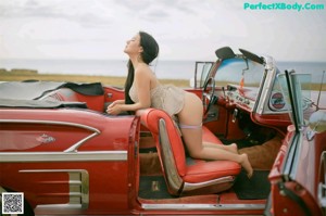 A woman sitting in the back of a red car.