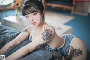 A woman in a blue and white polka dot swimsuit sitting on a chair.