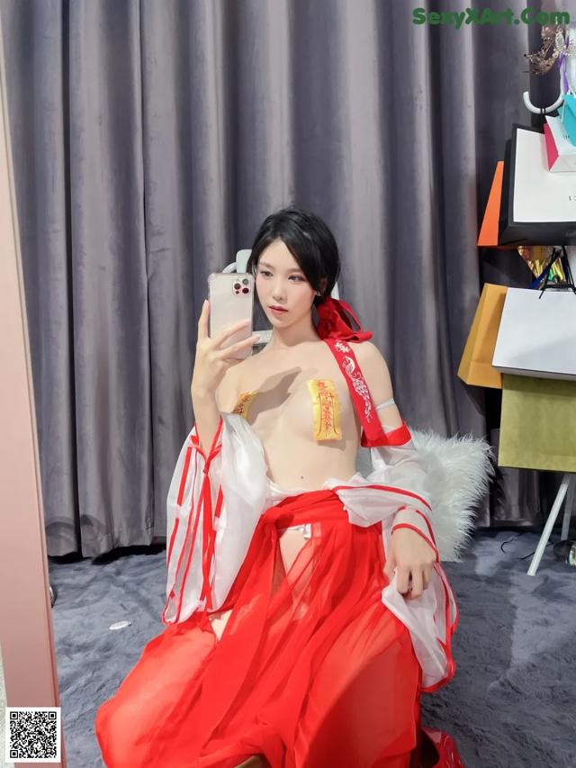 A woman in a red and white dress taking a selfie.