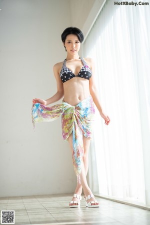 A naked woman sitting on a rug on the floor.