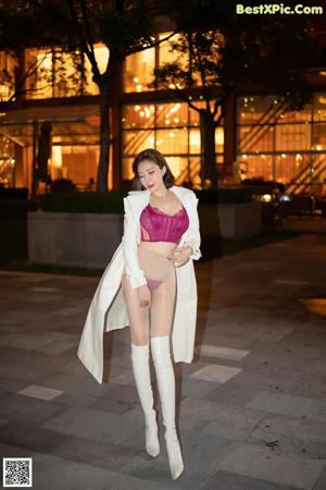 A woman in a white jacket and white boots posing for a picture.