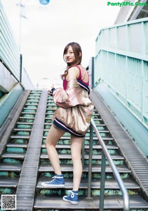 A young woman holding a baseball bat on a street.