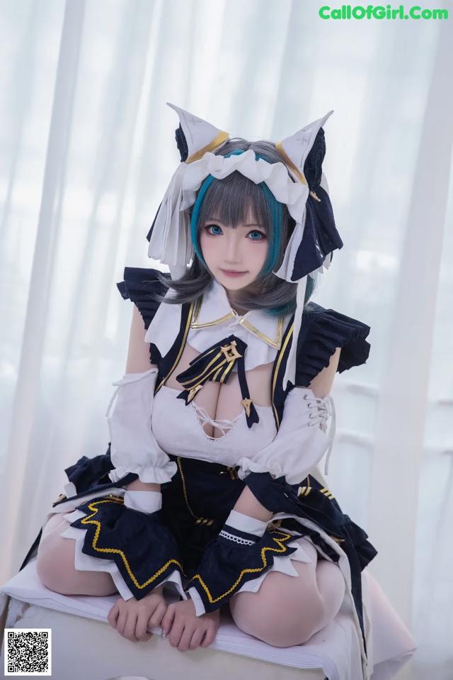 A woman in a black and white outfit sitting on a white box.