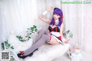 A woman with purple hair wearing a red and black outfit.