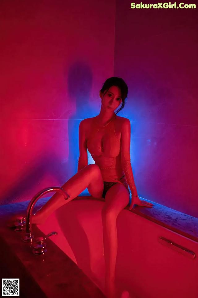 A woman sitting in a bathtub in a pink room.