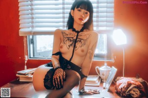 A woman in a white fur coat posing by a window.