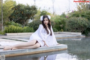 A woman in a white lingerie sitting in a pool.