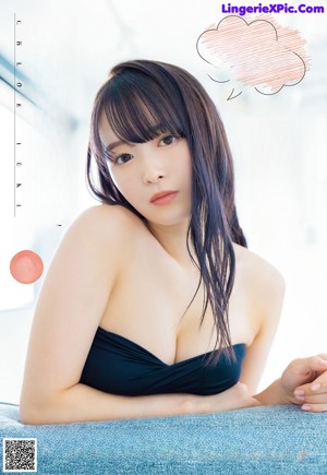 A woman in a black bikini laying on a bed.
