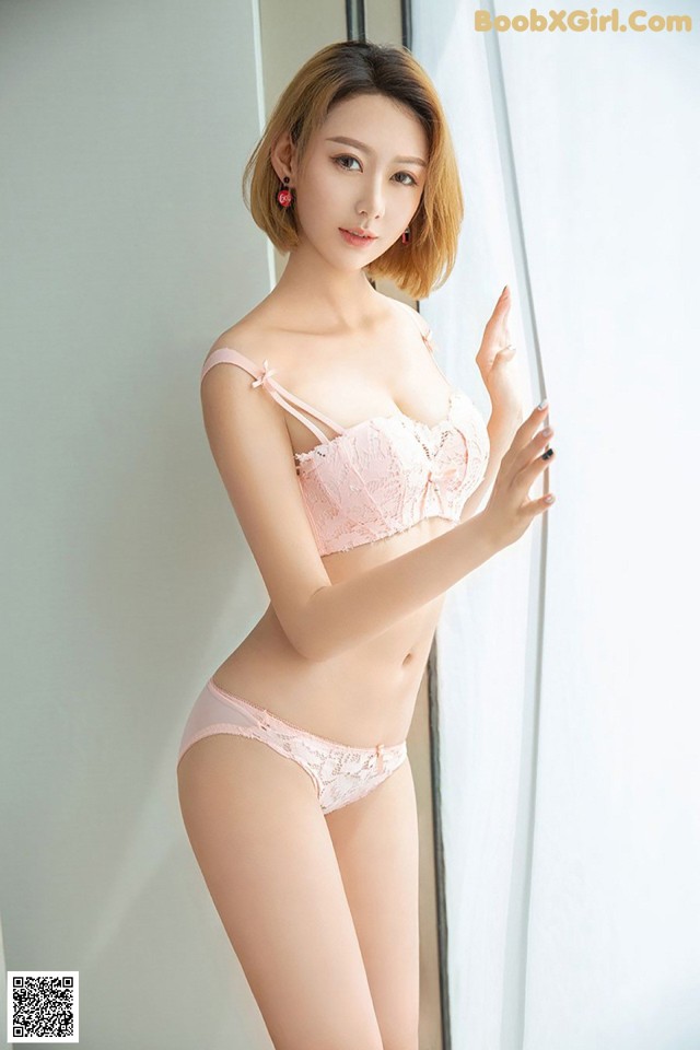 a woman in a pink lingersuit leaning against a wall