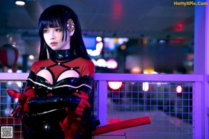 A woman in a black and red outfit holding a cat.