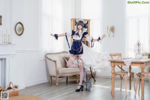 A woman in a maid outfit sitting on a chair.