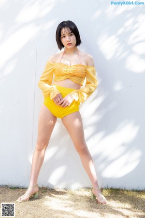 A woman in a yellow bikini sitting on a wicker chair.